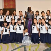 Uganda Ambassador Betty Grace Akech-Okullo (center) with Kanrei Shirayuri Gakuen elementary school students who participated in the Association of International Music exchange for Children program. | YOSHIAKI MIURA