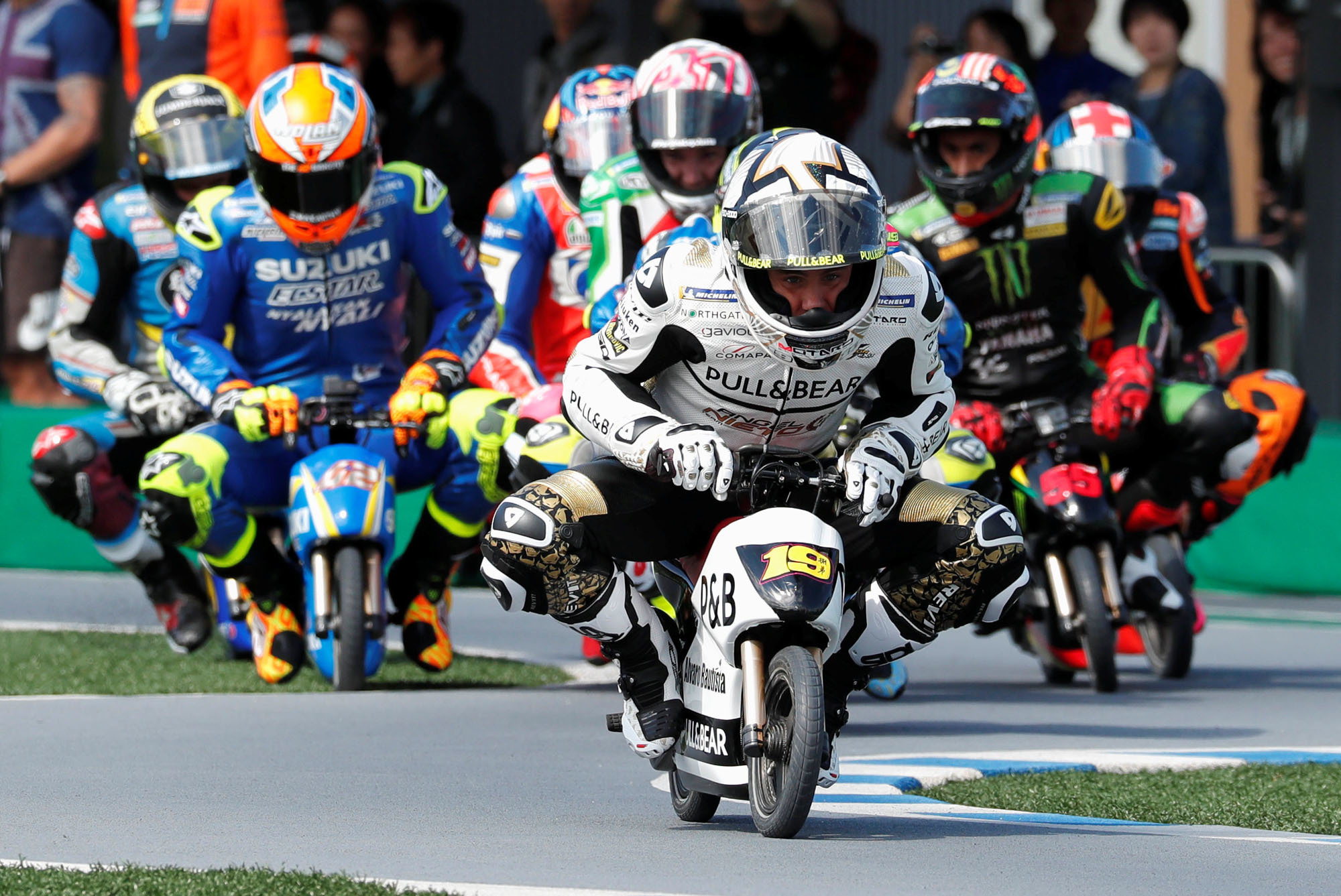 Alvaro Bautista (front), a rider for the Angel Nieto Team, and other MotoGP riders race mini-bikes during a fan event as part of festivities leading up to the Motul Grand Prix of Japan on Thursday. Pro riders teamed up with children in a pro-kid-pro relay over six laps on a kart track at the Twin Ring Motegi circuit in Motegi, Tochigi Prefecture, on Thursday. The Motul Grand Prix of Japan takes place Sunday. | REUTERS