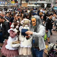 Revelers dressed up for Halloween take a selfie at the famed scramble crossing outside Shibuya Station in central Tokyo on Wednesday, the climax of the annual event. Hundreds of police officers were mobilized for crowd control. | YOSHIAKI MIURA