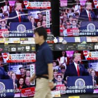 A man walks past TV screens showing U.S. midterm election reports Wednesday at an electronics store in Urayasu, Chiba Prefecture. | KYODO
