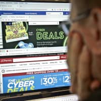 A journalist looks at a computer screen with webpages arranged to show Cyber Monday deals by various online retailers Monday in New York. The physical rush of Black Friday and the armchair browsing of Cyber Monday are increasingly blending into one big holiday shopping event as more customers buy items online and pick them up at brick-and-mortar stores. | AP