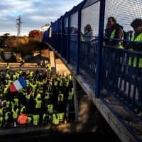 \"Yellow vest\" (Gilets Jaunes in French) protesters take part in a demonstration on the A6 motorway in Villefranche-sur-Saone, France, on Saturday to protest high fuel prices and living costs. Demonstrators who have blocked French roads over the past week dressed in high-visibility jackets were set to cause another day of disruption amid calls to bring Paris to a standstill. | AFP-JIJI