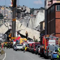 Firefighters and rescue workers stand at the site of the collapsed Morandi Bridge in the port city of Genoa, Italy, in August. | REUTERS