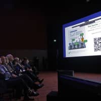 Members of the Microsoft Board and other audience members watch a video slide demonstrating a software feature called Microsoft Translator that can translate Microsoft PowerPoint presentations into other languages, as they attend the annual Microsoft Corp. shareholders meeting Wednesday in Bellevue, Washington. | AP