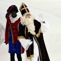 Sinterklaas, the Dutch Santa Claus, and assistant Zwarte Piet (Black Pete) appear during the speedskating World Cup at the Thialf Stadium in Heerenveen, the Netherlands, on Dec. 3, 2005. | REUTERS