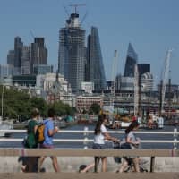 Pedestians cross the River Thames on Waterloo Bridge in August, with the City of London in the background. | AFP-JIJI