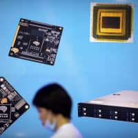 A visitor walks past a display showing microchips and circuit boards at the 21st China Beijing International High-tech Expo in Beijing on May 18. | AP