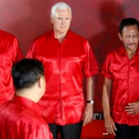 U.S. Vice President Mike Pence looks at Chinese President Xi Jinping as they prepare for a group photo with Asia-Pacific Economic Cooperation forum leaders at a gala dinner during the APEC summit in Port Moresby on Saturday. | REUTERS