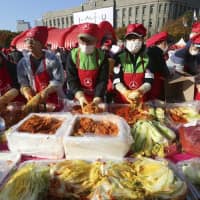 South Koreans make kimchi in an attempt at a Guinness World Record for largest number of people making kimchi at one place during the Seoul Kimchi Festival at Seoul Plaza on Sunday. More than 3,000 people made kimchi to donate to needy neighbors in preparation for the winter season. | AP