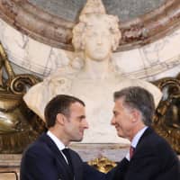 French President Emmanuel Macron (left) and Argentine President Mauricio Macri greet each other during a press conference at Casa Rosada presidential house in Buenos Aires on Thursday. | ARGENTINIAN PRESIDENCY / VIA AFP-JIJI