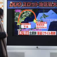 A pedestrian watches a screen broadcasting a map of Japan and the Korean Peninsula during a news program reporting on North Korea\'s missile launch, in Tokyo on Nov. 29 last year. | BLOOMBERG
