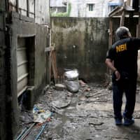 A member of the Philippine National Bureau of Investigation inspects the site where Kian Lloyd delos Santos, a 17-year-old student, was killed during anti-drug operations in Caloocan, Metro Manila, in August 2017. | REUTERS