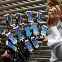 Chen San-yuan, 70, known as \"Pokemon grandpa,\" talks on his mobile phone as he plays the mobile game \"Pokemon Go\" near his home, in a Taipei suburb on Monday. | REUTERS