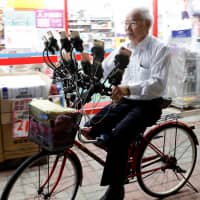 Chen San-yuan, 70, known as \"Pokemon grandpa,\" rides his bicycle as he plays the mobile game \"Pokemon Go\" near his home with 15 mobile phones, in a Taipei suburb on Monday. | REUTERS