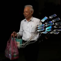 Chen San-yuan, 70, known as \"Pokemon grandpa,\" walks to his bicycle with 15 mobile phones as he prepares to play the mobile game \"Pokemon Go\" near his home in a Taipei suburb on Monday. | REUTERS