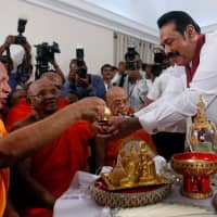 Sri Lanka\'s newly appointed prime minister, Mahinda Rajapaksa, is blessed by Buddhist monks during the ceremony to assume duties at the prime minister\'s office in Colombo on Monday. | REUTERS