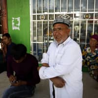A Uighur farmer stands outside a convenience store at the Unity New Village in Hotan, in the Xinjiang region of western China, on Sept. 21. | AP