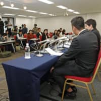 A man (left) who suffered severe burns to his face during a year-end party in 2015 holds a news conference Thursday in Tokyo, during which he revealed details of his plans to sue his former boss over the incident. | KYODO