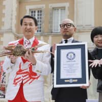 Tottori Gov. Shinji Hirai poses for a photo holding a snow crab Saturday in Tokyo at a promotional event. A crab caught in the prefecture earlier this month has been recognized by Guinness World Records as garnering the most expensive bid for a crab at &#165;2 million. | KYODO