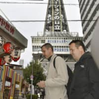 Foreign tourists visit the Shinsekai district of Osaka, famous for the Tsutenkaku tower, on Monday. | KYODO