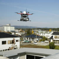 A Japan Post Co. delivery drone hovers over a post office in the town of Namie, Fukushima Prefecture, on Wednesday. | KYODO