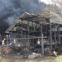 Firefighters examine a gutted house in Ono, Fukushima Prefecture, Thursday morning after a fire the night before killed seven residents. | KYODO