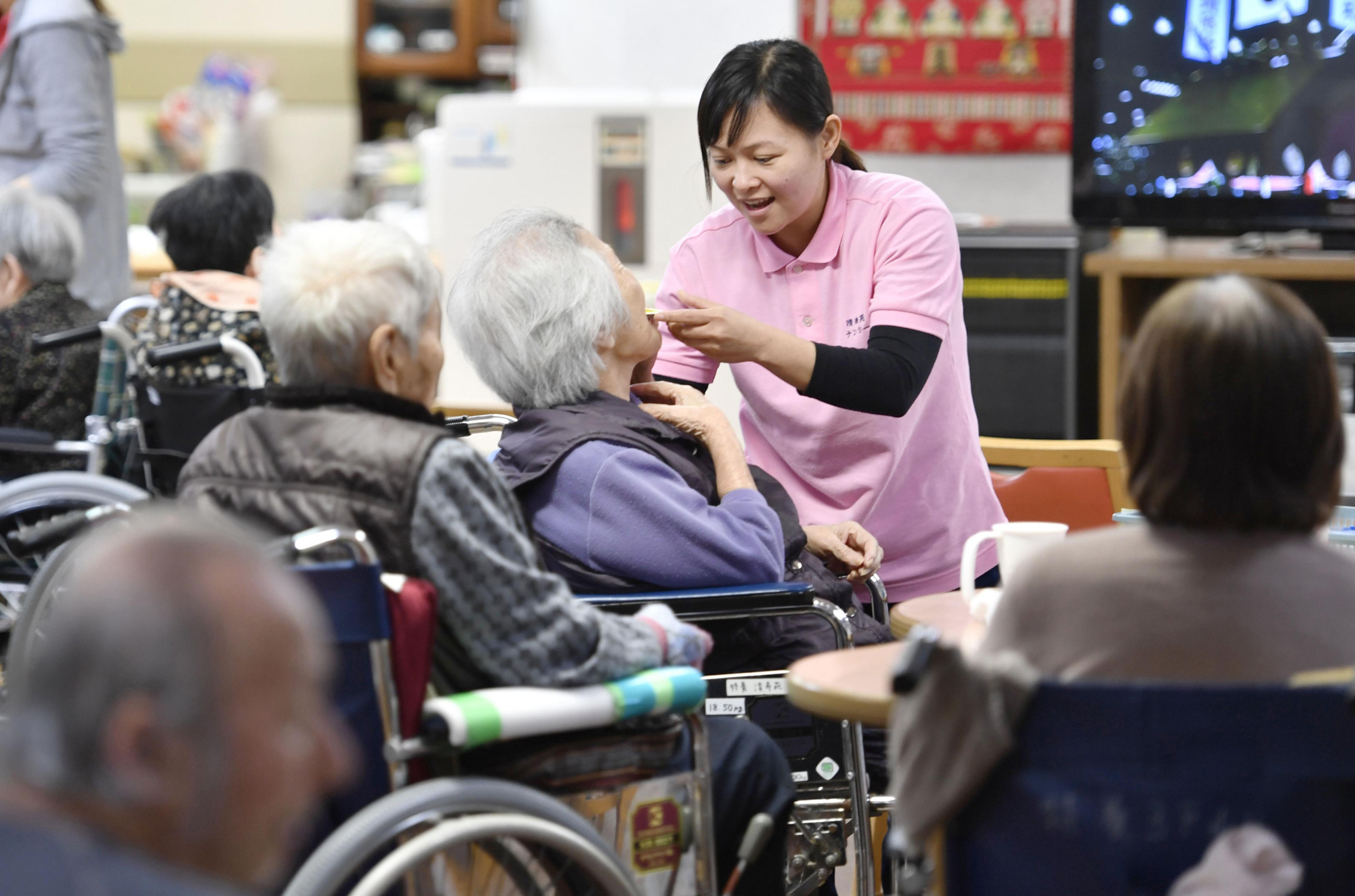 An Indonesian care worker tends to a resident at a facility in Tenri, Nara Prefecture, in May 2017. | KYODO