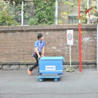 Sagawa Express Co. driver Keisuke Kawabe pushes his cart through the streets of Tokyo\'s Roppongi district while making a delivery last week. | ANDREW MCKIRDY