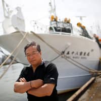 Shigeru Saito, captain of the squid fishing ship Hoseimaru No.58, poses in front of his boat at a port in Sakata, Yamagata Prefecture, on June 5. | REUTERS