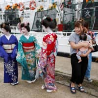 Entertainers wearing kimono attend a ceremony celebrating the departure of the squid fishing ships at a port in Sakata, Yamagata Prefecture, on June 6. | REUTERS