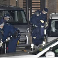 Police examine the area around the house where three people in a family were stabbed to death in Hirakata, Osaka Prefecture, on Thursday. | KYODO