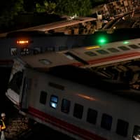 A worker walks around the derailed train in Yilan county, Taiwan, as preparations are made to clear the accident site on Oct. 22. | REUTERS