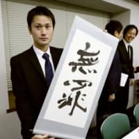 Tattoo artist Taiki Masuda holds a sign saying \"innocent\" Wednesday in the city of Osaka after the Osaka High Court overturned a lower court decision and acquitted the tattoo artist for operating without a medical license, ruling that the process is not a medical procedure. | KYODO