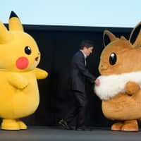 Right: Pokemon Co. CEO Tsunekazu Ishihara appears on stage with \"Pokemon\" characters Pikachu (left) and Eevee during a news conference in which the company unveiled the video games \"Pokemon: Let\'s Go, Pikachu\" and \"Pokemon: Let\'s Go, Eevee\" in Tokyo in May. The Nintendo Switch games were released on Nov. 16 | BLOOMBERG