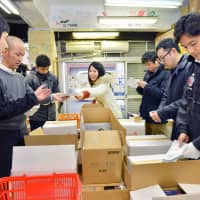 Helping hands: People pack boxes at Second Harvest Japan\'s central kitchen ahead of a distribution run. | COURTESY OF SECOND HARVEST JAPAN