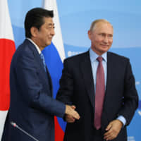 Prime Minister Shinzo Abe shakes hands with Russian President Vladimir Putin in September at the East Asian Summit, where Putin broached the idea of concluding a peace treaty by year\'s end \"without preconditions. | BLOOMBERG