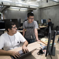 Carlos Perez Gutierrez (left), an engineer, speaks with a colleague at Line Corp.\'s R&amp;D facility in Kyoto. A small number of Japanese companies are now looking both inside and outside Japan for their new hires. | BLOOMBERG