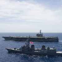 The Maritime Self-Defense Force destroyer Sazanami steams along side the USS Ronald Reagan in the South China Sea in October 2017. China is allowing the U.S. aircraft carrier and its battle group to make a port call in Hong Kong this week after it turned down a similar request amid tensions with Washington. | COMMANDER, U.S. 7TH FLEET PUBLIC AFFAIRS