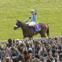 Jockey Christophe Lemaire salutes the crowd from atop Almond Eye after winning the Japan Cup on Sunday at Tokyo Racecourse. | KYODO