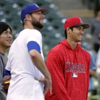Rangers reliever Chris Martin (left) and Angels hurler Shohei Ohtani, former Hokkaido Nippon Ham Fighters teammates, converse before a game on April 11 in Arlington, Texas. | AP