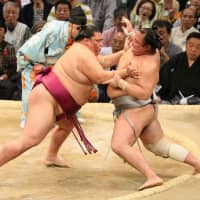 Sekiwake Mitakeumi (left) defeats No. 1 maegashira Hokutofuji at the Kyushu Grand Sumo Tournament on Friday. | NIKKAN SPORTS