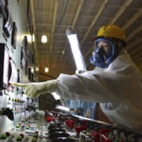 An official checks an instrument board in the main control room for crippled reactors Nos. 3 and 4 at the Fukushima No. 1 nuclear power plant last Thursday, as the facility is opened to media for the first time since the March 2011 meltdown. | KYODO