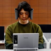 A designer at Panasonic Corp. demonstrates a prototype of Wear Space, wireless headphones designed to reduce surrounding noise and peripheral distractions, in October. | REUTERS
