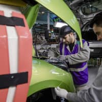 Employees fix fittings to a Nissan Micra automobile inside the Renault SA factory in Flins, France. | BLOOMBERG
