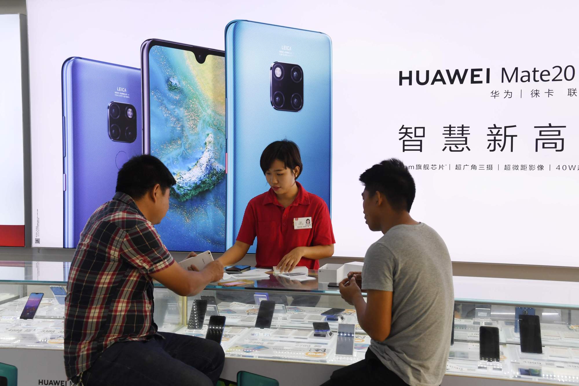 Customers are served at a Huawei stand at a store in southern China's Hainan Island. | AFP-JIJI