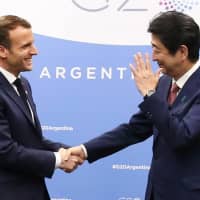 French President Emmanuel Macron shakes hands with Prime Minister Shinzo Abe during a meeting on the sidelines of the Group of 20 summit in Buenos Aires on Friday. | AFP-JIJI