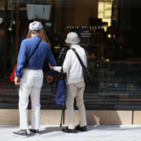 Shoppers look at bags displayed in a State of Escape store in the Tokyo\'s upscale Ginza district in May. The number of super-rich households in Japan has almost doubled since 2011 to a record high, thanks to rising stock prices and an economic expansion, an indication that this segment of society has benefited from Abenomics. | BLOOMBERG