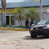 Policemen stand in front of the Banco do Brasil branch after a shootout with bank robbers in Milagres on Friday. | REUTERS