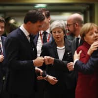 British Prime Minister Theresa May arrives for a round table meeting at an EU summit in Brussels Thursday. EU leaders gathered Thursday for a two-day summit that will center on the Brexit negotiations. At right is French President Emmanuel Macron greeting German Chancellor Angela Merkel. | AP