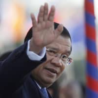 Cambodia\'s Prime Minister Hun Sen waves as he watches boat races during a water festival in Phnom Penh on Nov. 21. | AP